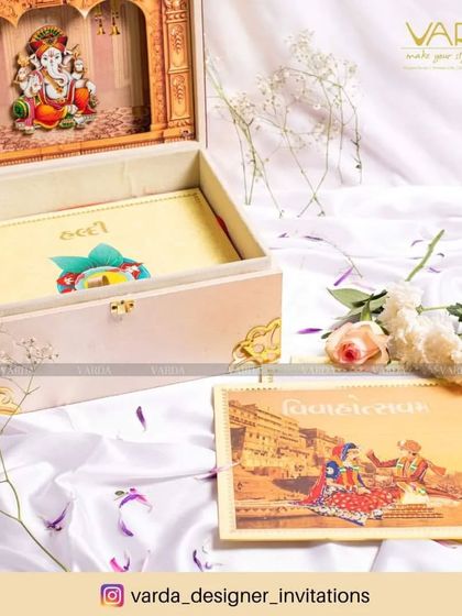 This beautiful invitation box features a 3D Ganesha idol set within a temple arch. The box itself is designed with a soft, elegant finish and comes with a wedding card that features a traditional ghat scene, perfect for a sacred ceremony.
