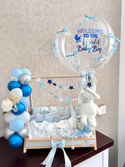 Welcoming a new baby boy is a huge deal, and this hamper is designed to match the occasion. We created a custom wooden clothing rack filled with baby essentials, complete with a personalized "Welcome to the World" balloon arrangement in shades of blue and silver.