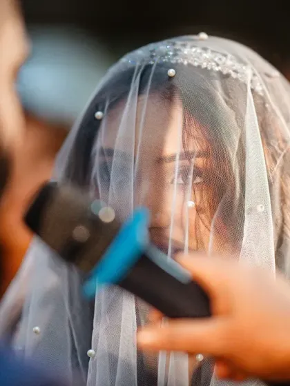 An intimate, close-up shot of the bride's face through her veil as she listens during the ceremony. It captures her focus and the solemnity of the moment.