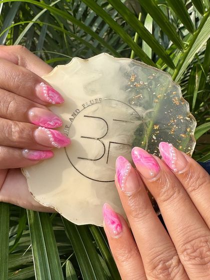 Elevate your style with a touch of elegance. These pink marble nails are adorned with delicate pearls for a sophisticated and unique look.