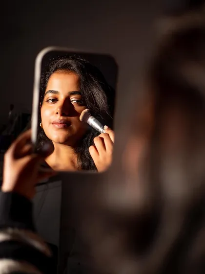 A creative portrait using a mirror to frame the subject. This shot tells a story about her craft as a makeup artist.