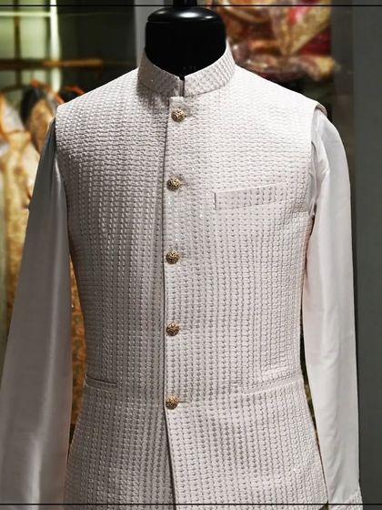 An off-white Nehru jacket with a subtle woven texture, paired with a white kurta. A great example of understated elegance.