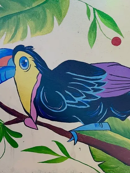 A close-up of the finished toucan, highlighting the bright blue beak and purple wing details against the green foliage.