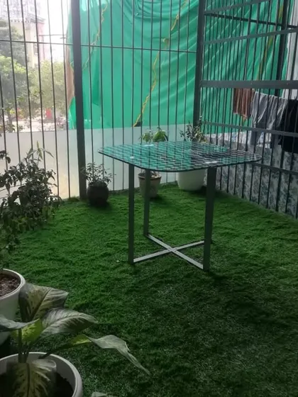 This caged balcony in Gurgaon now feels like a small yard thanks to a full carpet of artificial grass.