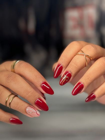 A festive and elegant red manicure. I added a hand-painted gold bow on one nail and a subtle glitter line on another for a touch of holiday cheer.