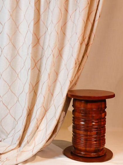 A close-up of one of our custom curtain designs. This elegant fabric features a delicate, embroidered trellis pattern that adds a layer of texture and sophistication to the window dressing.