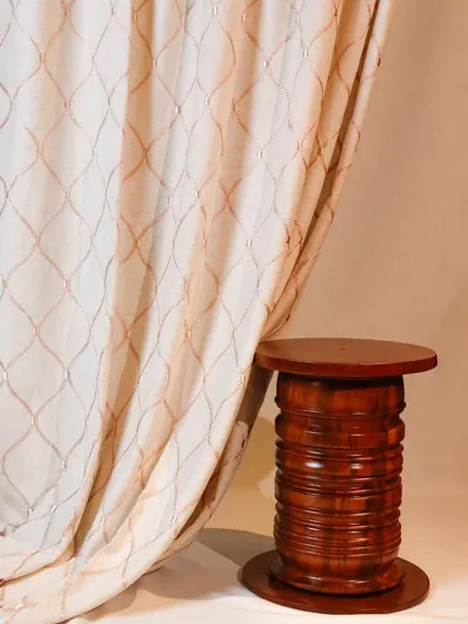 A close-up of one of our custom curtain designs. This elegant fabric features a delicate, embroidered trellis pattern that adds a layer of texture and sophistication to the window dressing.