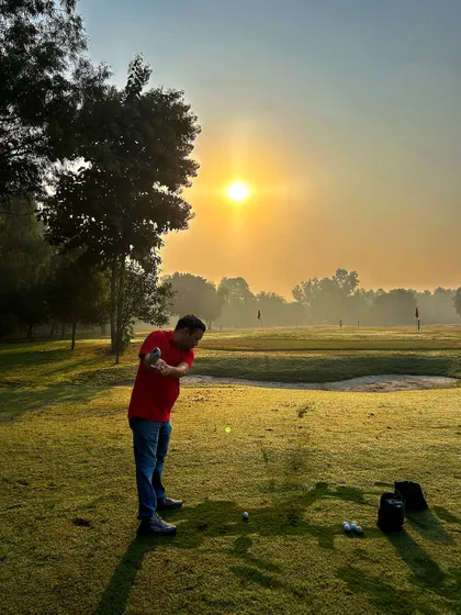 A golfer takes a practice swing against the rising sun, a perfect start to a day of grinding.