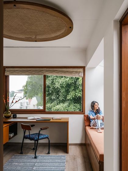 We designed this home office corner in Relic House to be a peaceful and inspiring nook. A simple wooden desk is paired with a comfortable chair, while the large window offers a view of the lush greenery outside. The window seat provides a perfect spot for reading or quiet contemplation.