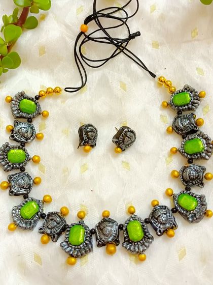 This unique necklace features small, alternating Durga face motifs and green stone-like beads. It's a more subtle way to wear a festive piece, with beautiful detailing in each small charm.