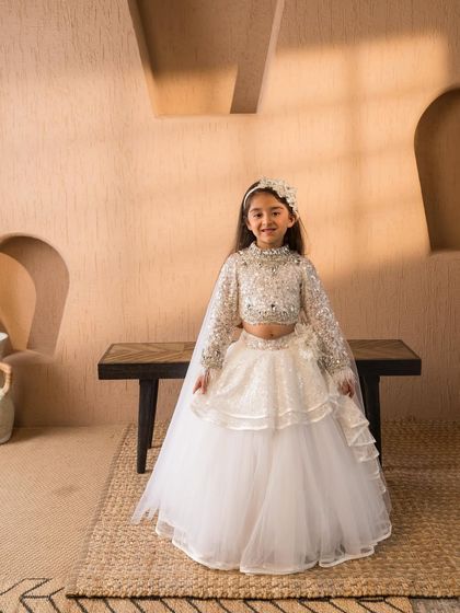 This full view shows the beautiful contrast between the sparkling blouse and the soft, flowing layers of the white lehenga skirt.