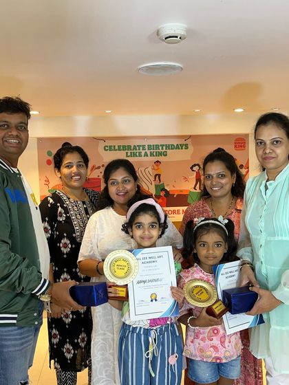 Two proud students with their families, holding their Abacus awards and certificates. Recognizing their hard work with trophies motivates them to keep learning.
