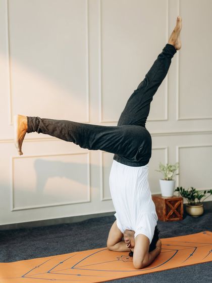 A dynamic expression of Sirsasana (Headstand) with legs in a wide split, showcasing advanced control and flexibility.