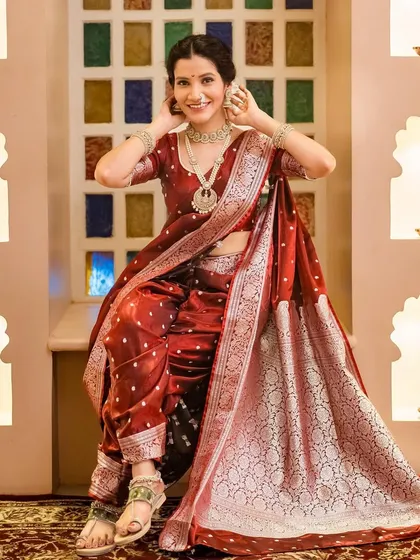 A graceful seated pose in the traditional maroon Navari saree, showcasing the rich fabric and jewelry.