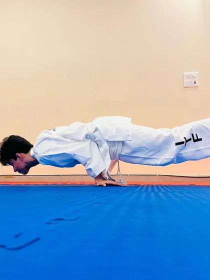 The perfect execution of a planche push up on the matted floor of our Dojang. This demonstrates the peak physical conditioning we aim for in our athletes.