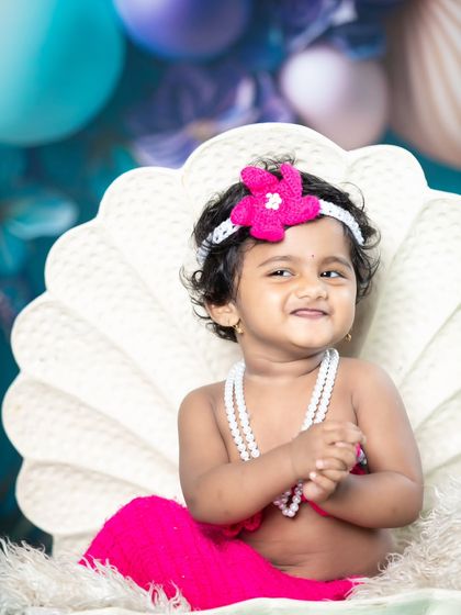 This little mermaid is all smiles, looking like an 'Expression Queen' in her seashell throne.