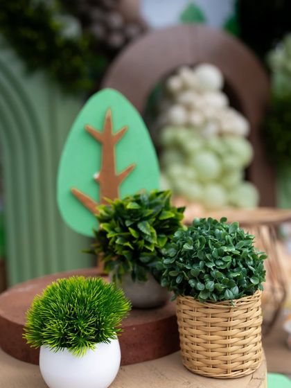 Small potted plants and a wooden tree cutout, part of the detailed table decorations that bring the woodland theme to life.