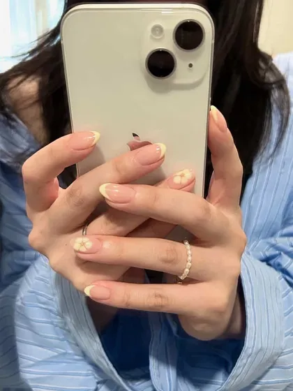 A soft and sweet take on the French manicure, with delicate, hand-painted yellow flowers on the accent nails.