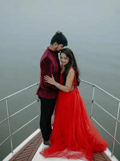 An intimate moment on a yacht. The bright red gown provides a stunning contrast against the water, creating a passionate and romantic pre-wedding photo.