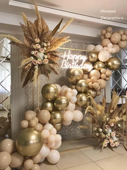 A close-up of the boho-chic setup, showing the detail of the dried pampas grass and floral arrangements mixed with the neutral and gold balloons. This style is perfect for a sophisticated, modern celebration.