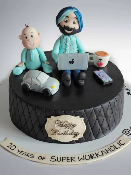 A cake celebrating "10 years of Super Workaholic". This design features a fondant figure of a man with his laptop and baby boy, representing the balance of work and family life.