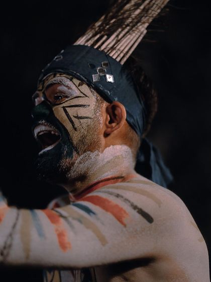 A close-up portrait of a performer with intense tribal face paint, mid-chant. This shot focuses on the raw emotion and cultural detail that makes these performances so powerful.