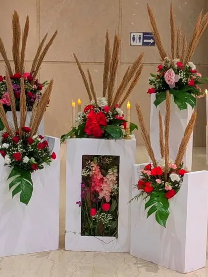 An artistic floral installation on modern white pedestals. I used red roses, pampas grass, and monstera leaves to create these unique arrangements, which can be used to define a space or as standalone decor pieces.