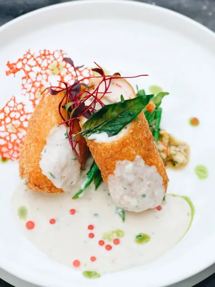 An elegantly plated dish of chicken cordon bleu. The bright, high-key lighting and clean composition give this shot a fine-dining feel, perfect for a high-end restaurant menu.