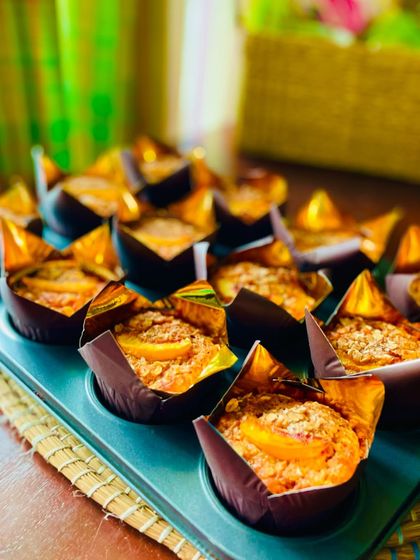 A close-up of the muffins, showing the beautiful texture and the slice of peach on top.