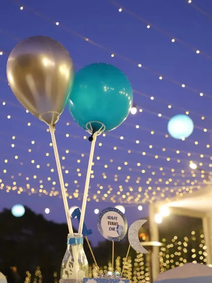 A beautiful evening shot of the party ambiance. The table centerpiece balloons are silhouetted against a sky of twinkling fairy lights, creating a truly magical atmosphere.