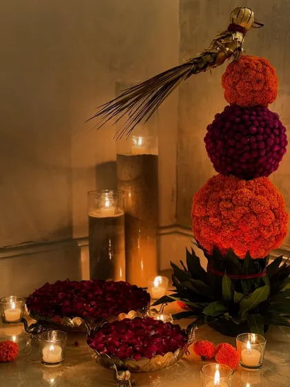 For Diwali, I love creating welcoming arrangements for a guest's arrival. This one-of-a-kind display features a topiary of marigold and gomphrena spheres, surrounded by bowls of petals and glowing candles.