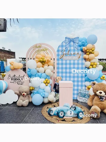 A charming teddy bear party setup on a rooftop. This "Brotherhood" theme for a joint birthday uses a blue and tan color palette with a cute gingham-patterned backdrop.