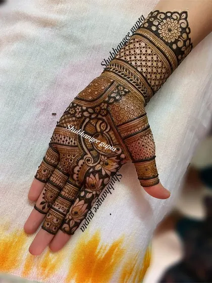 Even a simpler bridal design can be very elegant. This piece features a central Ganesh motif for blessings, surrounded by lotus flowers and delicate patterns on the fingers.