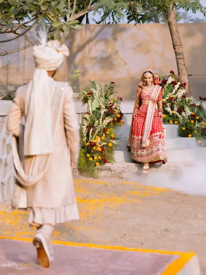 The groom walks towards his bride, who waits for him at the top of the steps, a moment of anticipation before they unite.