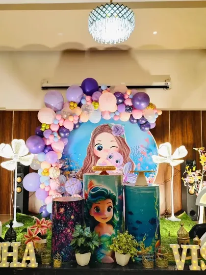 A wide shot of the mermaid-themed joint birthday party for Aksha and Visha, showing the full arrangement with light-up numbers.