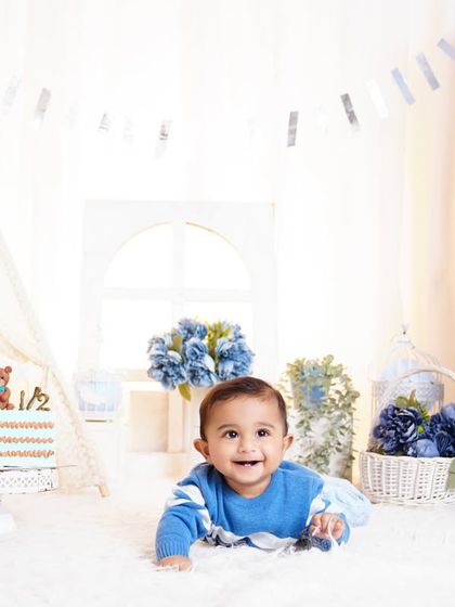 A happy baby boy crawling towards the camera during his six-month photoshoot, set against a fun blue-themed backdrop.