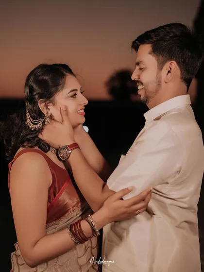 A candid and happy close-up of a couple by the water at dusk, their smiles showing their genuine joy.
