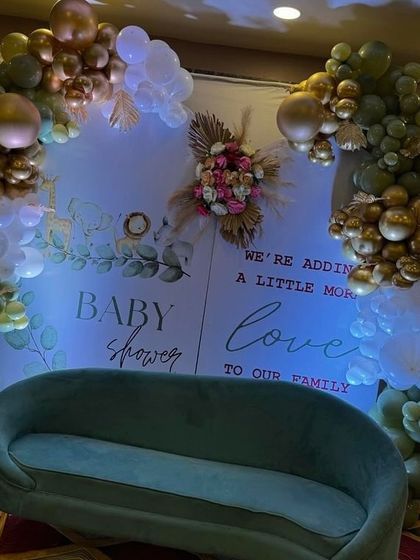 A beautifully lit shot of the olive green and gold baby shower backdrop, creating a sophisticated and warm atmosphere.