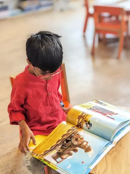 A young boy completely captivated by the illustrations in his book. This is the magic of reading we hope to inspire.