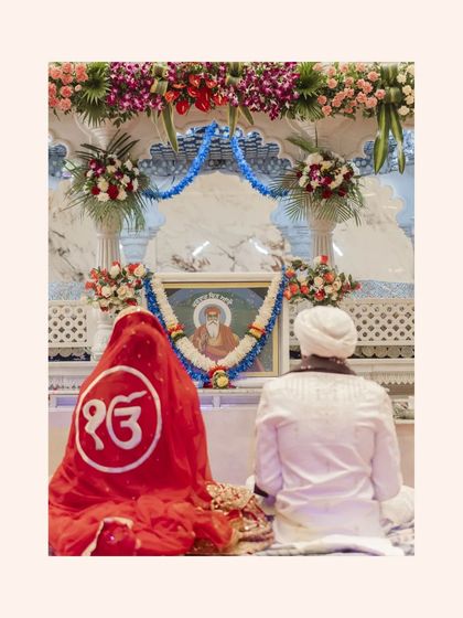 A serene moment of prayer at the Gurudwara, the couple sitting before a portrait of a Guru.