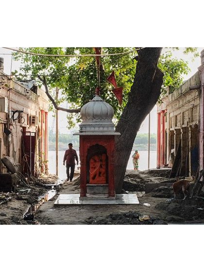 The aftermath of a flood on the ghats of the Yamuna River. A small shrine stands resiliently amidst the mud and debris, a symbol of enduring faith.