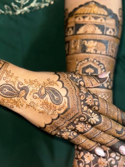 A detailed shot of the arm and hand, showing the combination of peacock and architectural motifs.