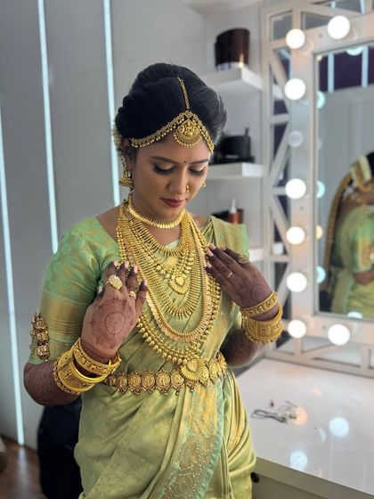 A moment of final adjustments for Harina. She looks into the mirror, admiring her complete bridal look, from the flawless makeup to the perfectly draped saree.