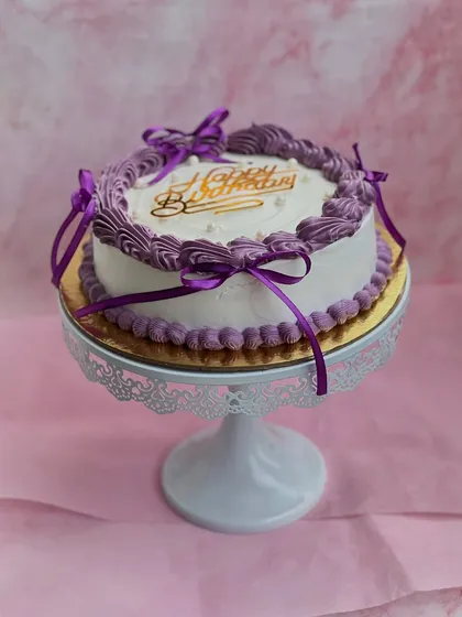 Vintage vibes and violet dreams! This beautiful birthday cake features delicate purple buttercream piping and is tied with satin ribbons for a classic, elegant look.