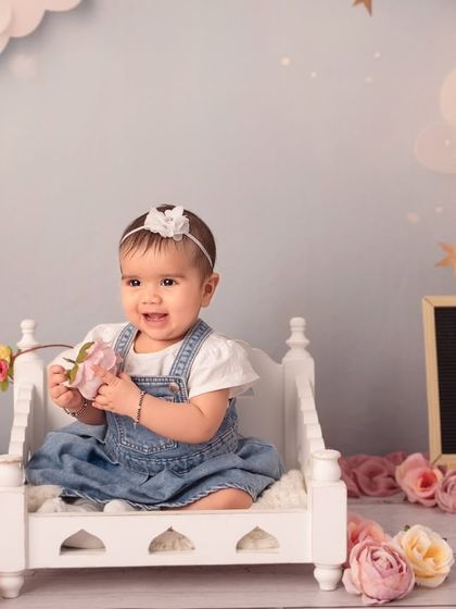 Sitting pretty on a miniature bed surrounded by flowers. Sitter sessions are perfect for using cute props now that your baby can support themselves.