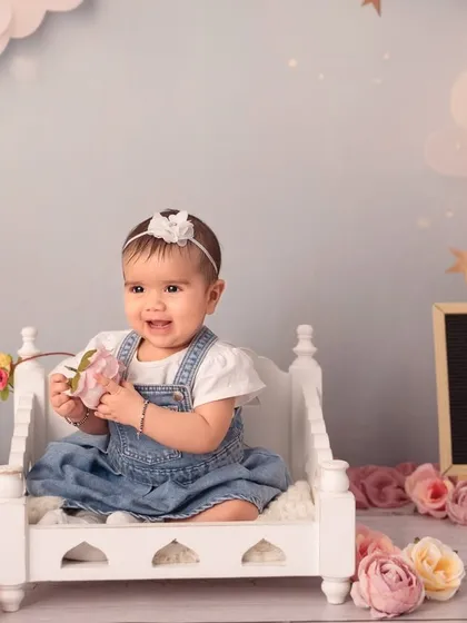 Sitting pretty on a miniature bed surrounded by flowers. Sitter sessions are perfect for using cute props now that your baby can support themselves.