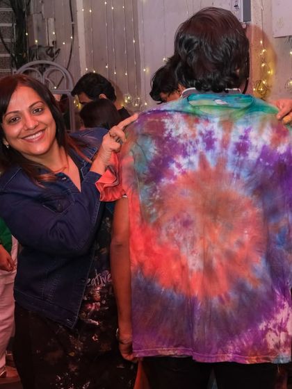 A participant at a party shows off the vibrant tie-dye shirt she made. It's always fun to see the unique patterns and color combinations everyone comes up with.