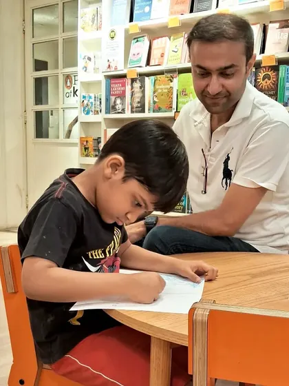 A father and son spending quality time together, focused on a drawing. These are the moments we cherish.