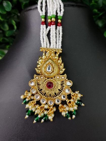A traditional beaded maang tikka with a sun-like pendant design.