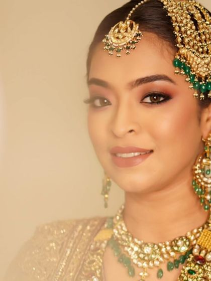A beautiful portrait showcasing a glamorous smokey eye. The deep tones and touch of glitter make her eyes the focal point, perfectly complementing her ornate traditional jewelry.